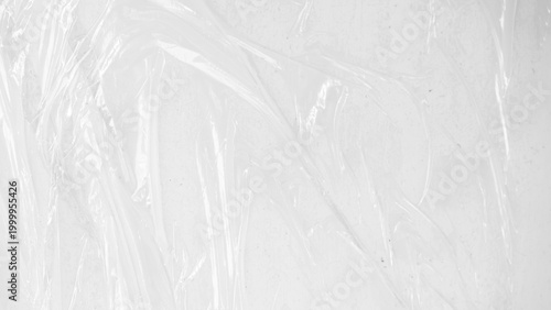 plastic transparent cellophane bag on white background. The texture looks blank and shiny. The plastic surface is wrinkly and tattered making abstract pattern