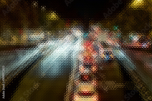 Urban lights creating a dynamic abstract pattern and bokeh effect through a textured surface