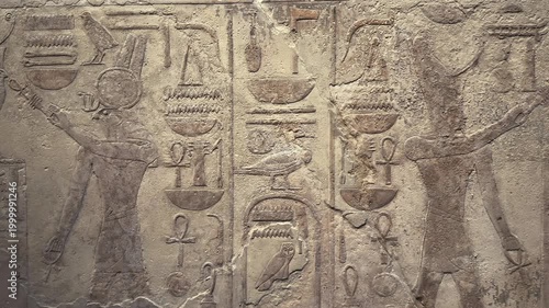 Close or medium shot of ancient Egyptian carved stone relief with hieroglyphs