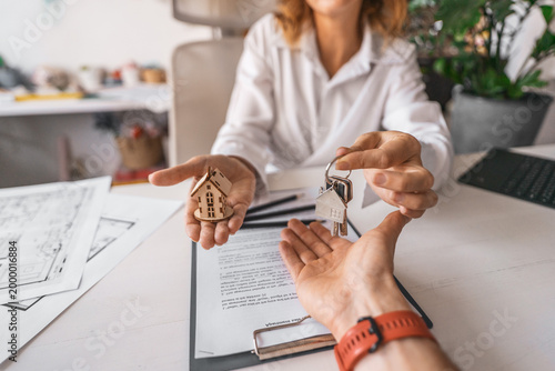 Tableau sur toile Female realtor signed contract for apartment sale rental and hands keys client over documents with blueprint and house model on table