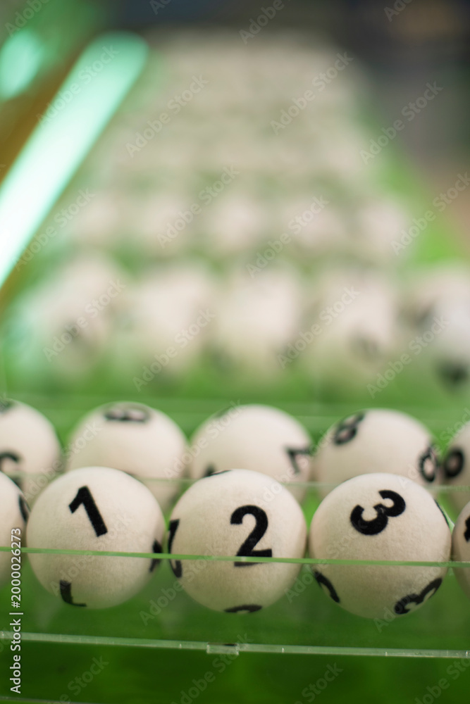 Naklejka premium Vertical Perspective of Numbered Lottery Balls with Green Neon Light