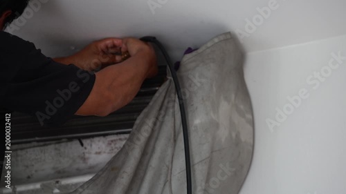Professional technician using a high-pressure water spray to deep clean an air conditioner's evaporator coils with a protective water-catch cover.