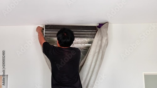 Professional technician using a high-pressure water spray to deep clean an air conditioner's evaporator coils with a protective water-catch cover.