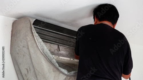 Professional technician using a high-pressure water spray to deep clean an air conditioner's evaporator coils with a protective water-catch cover.