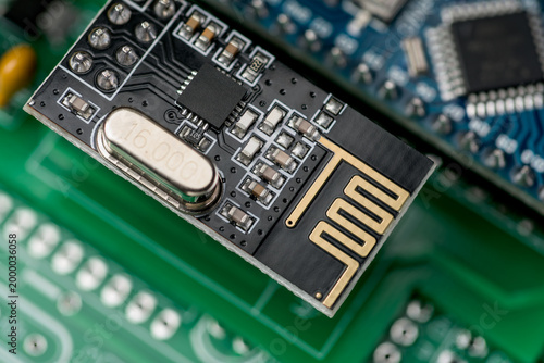 Fotografie Black wireless module with PCB antenna and electronic components on a green circuit board