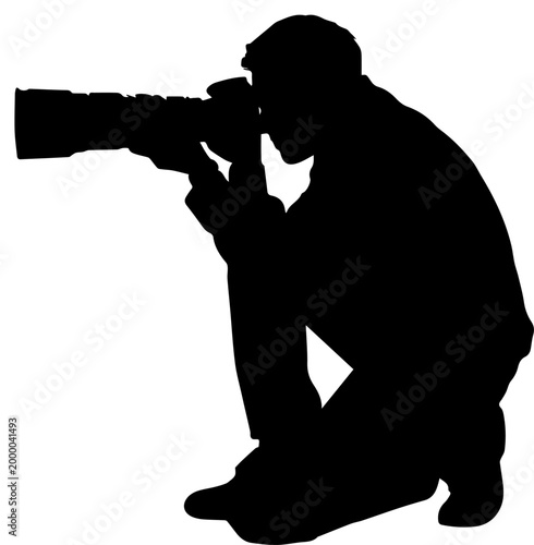 Silhouette of a Professional Photographer Kneeling and Taking Pictures with a Large Telephoto Lens