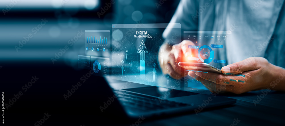 Obraz premium Business professional using smartphone with digital dashboard interface labeled digital transformation, showing data charts, analytics panels, and network visualization for modern business technology