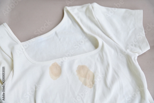 Close up of yellow food or coffee stains on a white t-shirt, dirty clothes concept