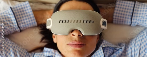 Fotografie Woman with eye massage device lying on sofa