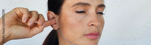 Foto Woman scratching inside of ear with finger
