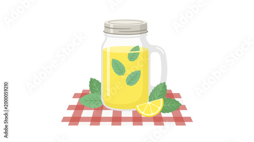 A glass mason jar filled with yellow lemonade sits on a red and white checkered tablecloth with a lemon slice and mint leaves