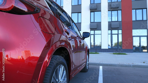 Foto Cars and building are reflected in the red surface of a modern car parked in fro