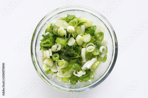 Konstfotografi Top view of a clear glass bowl of sliced or chopped green spring onions, isolated on a clean white background