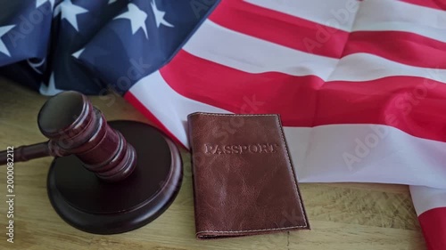 Passport and gavel placed on a table next to American flag during a legal discussion or travel planning moment