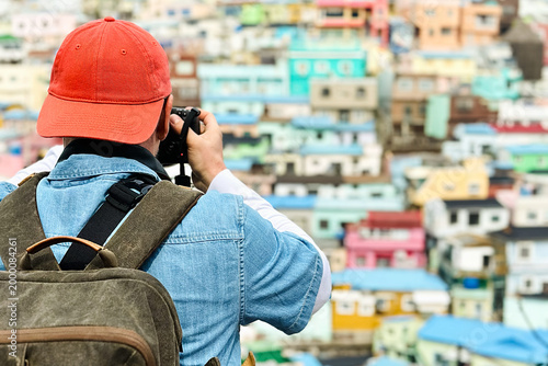 Tourist in an orange cap takes a photo of the Gamcheon Cultural Village in South Korea.