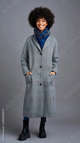 African female young adult long coat scarf boots full length fashion pose gray backdrop confident style