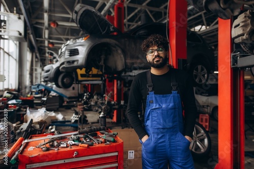 Mechanic in blue overalls standing in car workshop