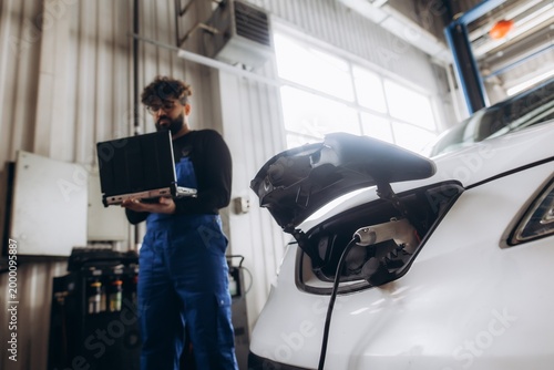 Cuadro en lienzo Mechanic diagnosing electric car charging at workshop