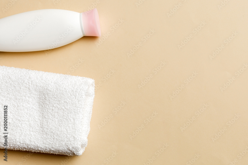 Obraz premium Cosmetic shampoo bottle mockup with towels on a colored table. Bathroom background, toilet accessories for hand and body care