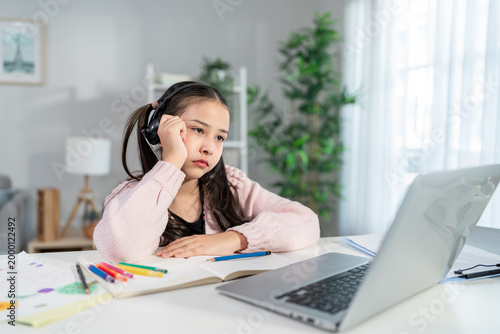 Asian young stressed kid learning online class with teacher at home. 
