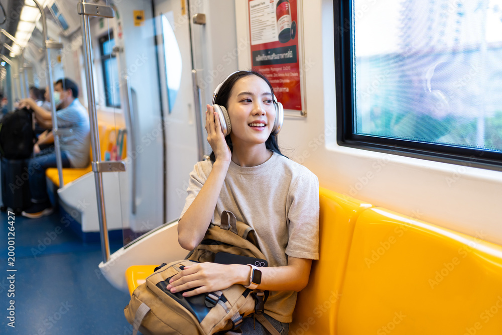Naklejka premium Asian young woman sitting on subway train seat while traveling in city.