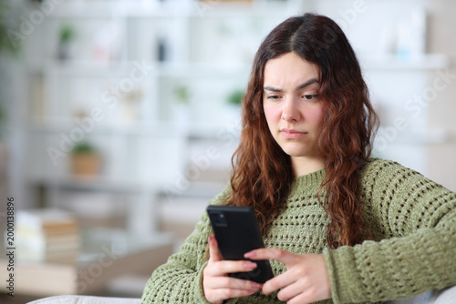 Schilderij op canvas Suspicious young woman checking phone at home