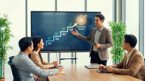 Successful business team strategy meeting for growth and achievement with professional manager presenting quarterly kpi target goal on digital screen in modern office for corporate success and profit.