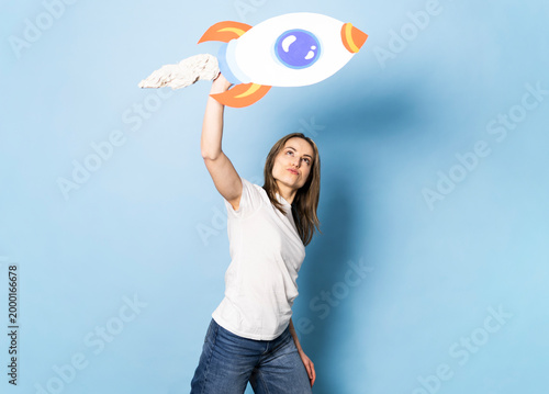 Woman holding a handmade paper rocket symbolizing success and ambition