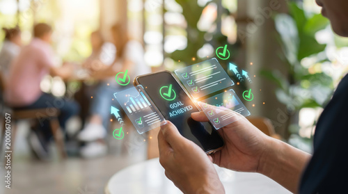 Business Success and Growth Strategy Concept with Person Using Smartphone to Track KPI and Goal Achievement via Digital Holographic Interface Showing Progress Data and Performance Results.