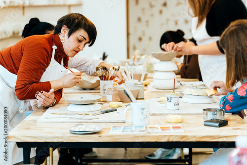 Slika na platnu People enjoying creative ceramic painting workshop, making handmade artisanal po