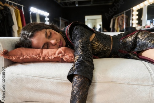 Φωτογραφία Young female actress sleeping on a sofa, wearing a costume in a dressing room ba