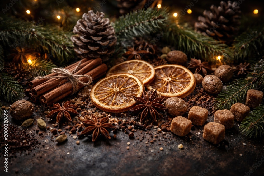 Naklejka premium Dark background presentation of Christmas spices combined with pinecones and dried fruits for seasonal festive inspiration