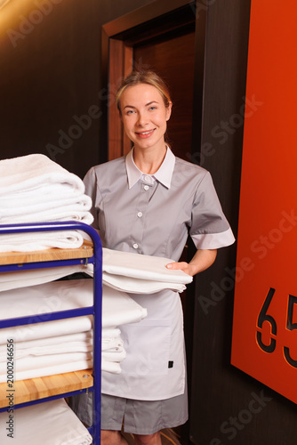 Foto Friendly housekeeping staff member with linen cart standing in luxury hotel hall