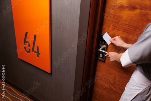 Foto Hotel housekeeper opening guest room door with keycard in modern hallway closeup