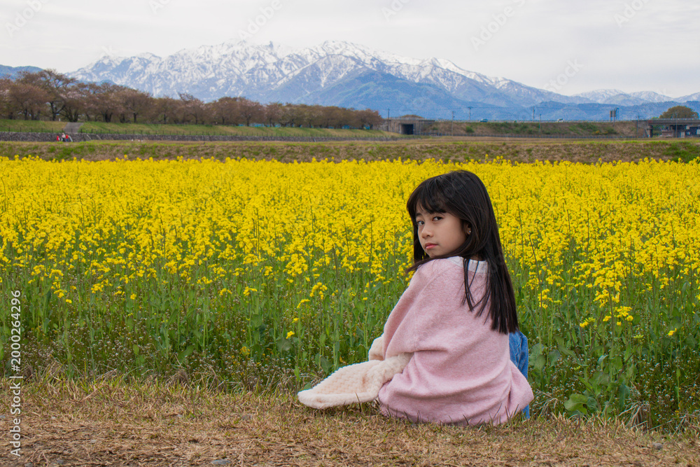 Fototapeta premium Girl in Yellow Flower Field with Mountains