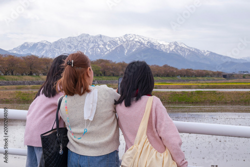 Three Women Taking Photos of Snow-Capped Mountains