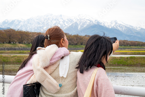 Three Women Taking Photos of Snow-Capped Mountains