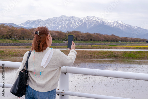 Woman Photographing Snow-Capped Mountains with Phone