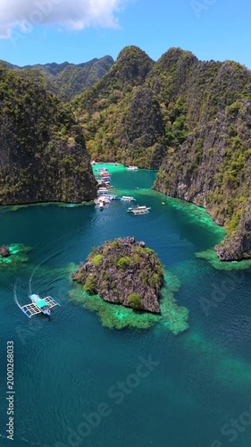 Aerial view of tropical lagoon near Kayangan Lake in Coron, Philippines. Boats anchored in turquoise water surrounded by limestone cliffs in crystal clear tropical bay.