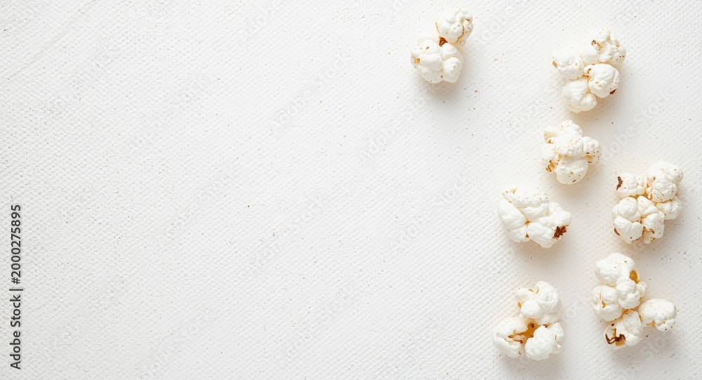 Obraz premium White textured background with ample copy space featuring isolated popcorn kernels