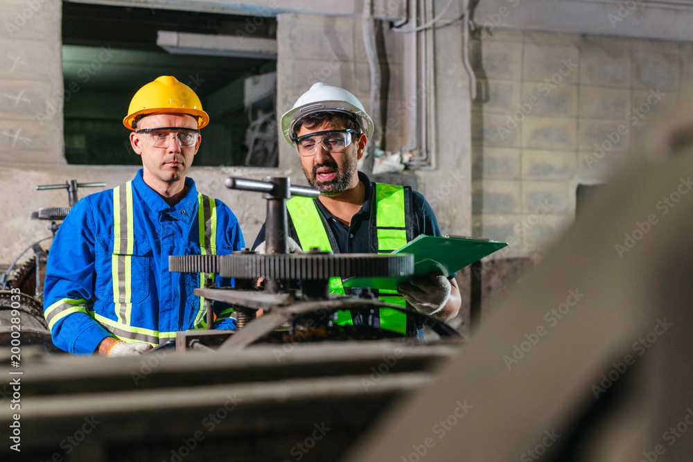 Fototapeta premium Factory Technicians Performing Heavy Machine Maintenance in Traditional Metal Workshop