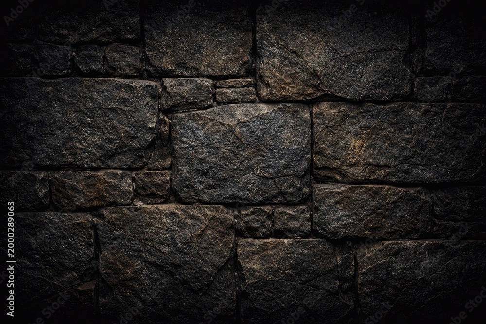Fototapeta premium Highly detailed stone wall texture with natural weathering and dark black backdrop