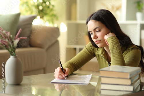 Young woman filling out form on a coffee table at home