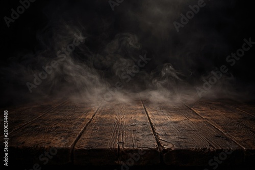 Dark backdrop with smoke hovering above an old wooden tabletop