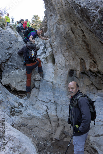 Bilde på lerret Group of hikers rock scrambling and climbing through a narrow rocky canyon in na