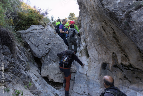 Photography Group of hikers scrambling a rocky canyon wall, navigating challenging terrain d