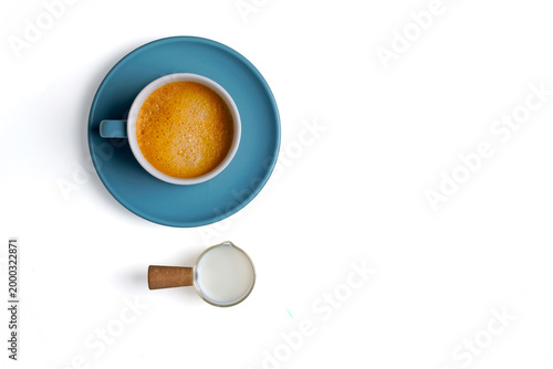 Coffee cup and a jug of fresh milk on a white background.