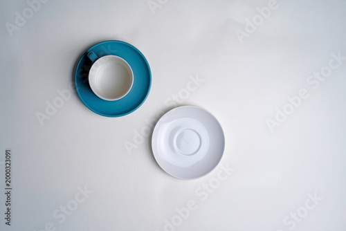 ฺBlue coffee cup and an empty white saucer on a white background.