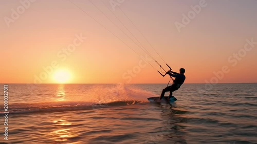 Person kitesurfing on ocean waves at sunset with kite and board