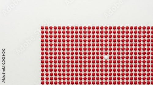 A single contrasting medical pill stands out amidst a collection of identical ones